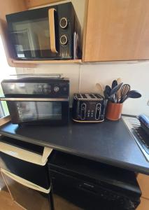 a kitchen counter with a microwave and a toaster oven at Buxton's Holiday Home - 'Park Holiday's' complex - St Osyth - Clacton-on-Sea in Saint Osyth +29 photos