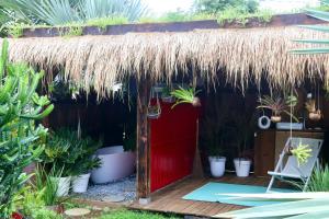 a hut with a thatched roof and a red door at Le Baobab Rouge - Maison d'hôtes réservée aux femmes in Le Lamentin