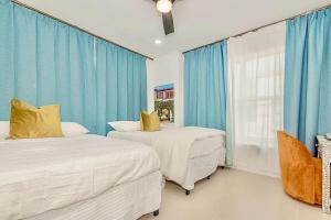two beds in a room with blue curtains at 2-Min to Beach, Upscale Enclave in Miami Beach +50 photos
