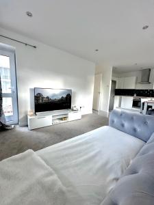 Un dormitorio blanco con una cama y un televisor de pantalla plana. en Luxury Apartment Oxford, en Abingdon