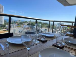 einen Tisch mit Weingläsern und Tellern auf dem Balkon in der Unterkunft Pôr do Sol na Barra I in Salvador