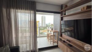 ein Wohnzimmer mit einem TV und einem großen Fenster in der Unterkunft Pôr do Sol na Barra I in Salvador