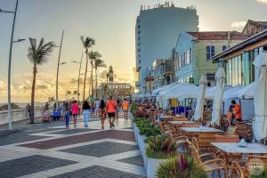 eine Gruppe von Menschen, die eine Straße mit Tischen und Stühlen entlang gehen in der Unterkunft Pôr do Sol na Barra I in Salvador