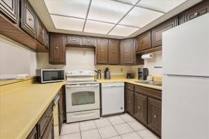 a kitchen with wooden cabinets and white appliances at Charming Beach Condo in St Augustine in Saint Augustine
