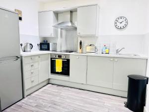 a kitchen with white cabinets and a clock on the wall at Luxury City Centre Apartment in Edinburgh +22 photos