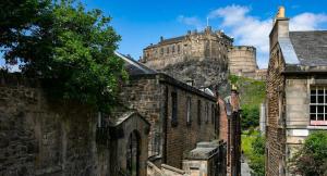 an old brick building with a castle in the background at Luxury City Centre Apartment in Edinburgh