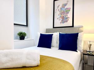 a bedroom with a bed with blue pillows at Luxury City Centre Apartment in Edinburgh