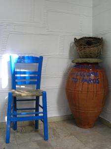 niebieskie krzesło siedzące obok dużej wazy w obiekcie Pension Chanioti w mieście Parikia