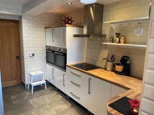 a kitchen with white appliances and a wooden counter top at Coaltown Cottage Cosy 4 bed cottage with log burner, close to Gower beaches in Dunvant +31 photos