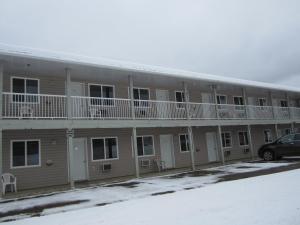 a building with balconies and a car parked in front at Kacee's Northern Suites in Fort Nelson