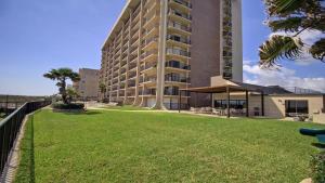 a large building with a green lawn in front of it at SPI FUN! - Beach View - 2025 Full Remodel - 2BR Condo OV502 in South Padre Island