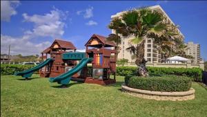 a playground with a slide in the grass at SPI FUN! - Beach View - 2025 Full Remodel - 2BR Condo OV502 in South Padre Island