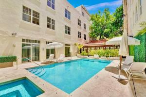 a swimming pool with chairs and umbrellas next to a building at 2-Min to Beach, Upscale Enclave in Miami Beach