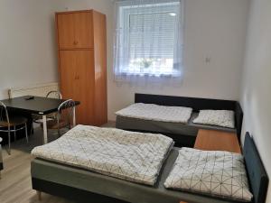 a room with three beds and a table and a window at Noclegi Bełchatów in Bełchatów