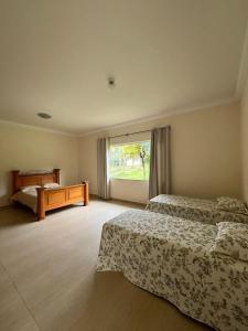 a hotel room with two beds and a window at Mansão com vista para lago in Ijaci +10 photos