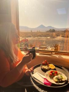 a woman taking a picture of a plate of food at Bangalô Ayllu Atacama in San Pedro de Atacama