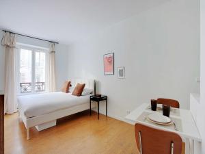 a white bedroom with a bed and a table at Modern and Cosy Studio - 2P - Rueil-Malmaison in Rueil-Malmaison