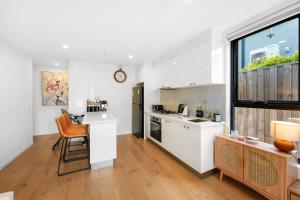 a kitchen with white cabinets and a large window at XV - Sun Soaked Ultimate Bentleigh Convenience in Melbourne +7 photos