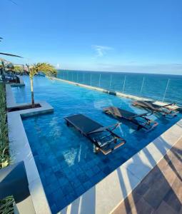 a infinity pool with two beds and the ocean in the background at Apartamento charmoso com Rooftop in Salvador