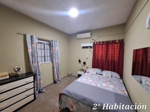 een slaapkamer met een bed, een ladekast en een raam bij Alojamiento Marlugm in Corrientes