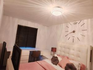 a bedroom with a clock on the wall and a bed at Mareot House UK in Havering atte Bower