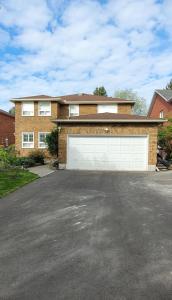 a large brick house with a white garage at Holiday Hideout Basement Unit in Pickering