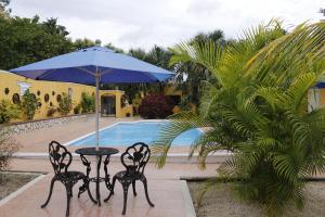 a table and chairs with an umbrella next to a pool at Posada Ya´ax Ich in Izamal