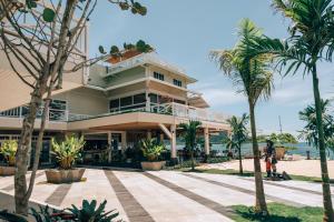 a building on the beach with palm trees in front at Amaka Ocean Living Lodge in Golfito