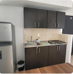a kitchen with black cabinets and a sink and a refrigerator at David Cómodo Apartamento con Piscina in Armenia