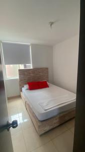 a bed with a red pillow in a room at David Cómodo Apartamento con Piscina in Armenia