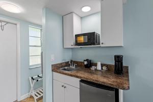 a kitchen with a sink and a microwave at Oceanfront Inn Room #18- Ocean View Balcony 2 Full Beds in Fort Pierce