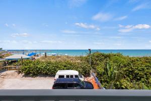 a truck parked on a beach near the ocean at Oceanfront Inn Room #20- Ocean View Balcony 2 Full Beds in Fort Pierce