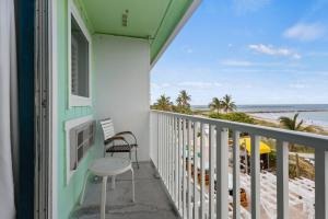 a balcony with a table and a chair and the beach at Oceanfront Inn Room #22- Ocean View Balcony 2 Full Beds in Fort Pierce