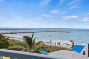 a view of a beach with people in the water at Oceanfront Inn Room #22- Ocean View Balcony 2 Full Beds in Fort Pierce