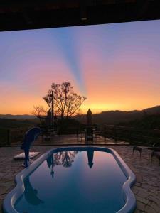 a swimming pool with a sunset in the background at Chácara João e Maria in Toledo +7 photos