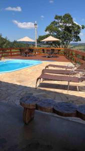 a swimming pool with benches and tables next to a pool at Chácara João e Maria in Toledo
