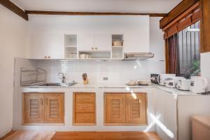 a kitchen with white walls and wooden cabinets at Thongkwao house in Chiang Mai