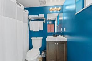 a blue bathroom with a toilet and a sink at Oceanfront Inn Room #21- Ocean View Balcony King Bed in Fort Pierce