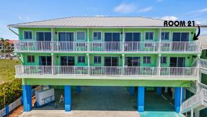 a large green house with a balcony at Oceanfront Inn Room #21- Ocean View Balcony King Bed in Fort Pierce