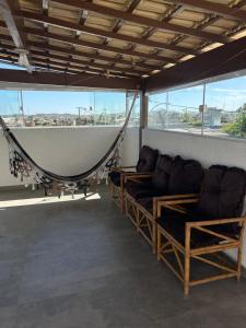a room with couches and a hammock on a balcony at Casa temporada Cabo Frio Casa pôr do Sol in Cabo Frio