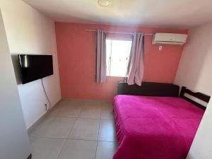 a small bedroom with a pink bed and a window at Casa temporada Cabo Frio Casa pôr do Sol in Cabo Frio