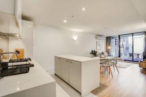 a kitchen with white cabinets and a dining room at Neo200 - Sophisticated 2bed CBD Apt with parking in Melbourne +11 photos