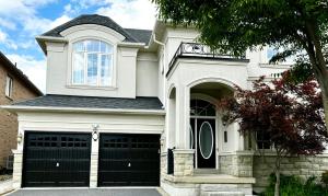 una casa bianca con due porte nere per il garage di 3500 SqFt - Modern and Comfort - 4 BDRM Getaway - Relax - Unwind - Explore - Near Airport & Toronto Downtown a Brampton