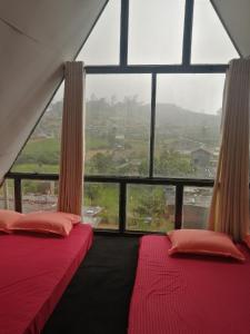 two beds in a room with a large window at Hiranya frame house in Pattipola