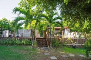 a house with two palm trees and a fence at Exotic Villa avec Piscine in Le Vauclin