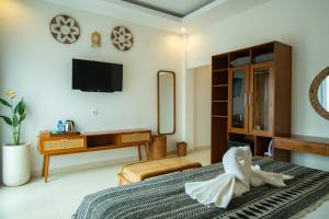 a bedroom with a bed and a desk and a tv at Wakasuta House in Ubud