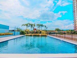 a large swimming pool with palm trees in a building at Cebu stays-Saekyung 956 Condominium unit 1209 in Lapu Lapu City