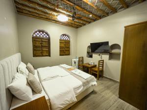 a bedroom with a bed and a table and a television at IHYAA Inn - نزل إحياء in Nizwa