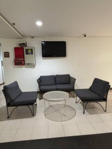 a room with a couch and two chairs and a table at 1-bedroom Condo Unit with PS5, Netflix & Pool near SM Fairview in Manila