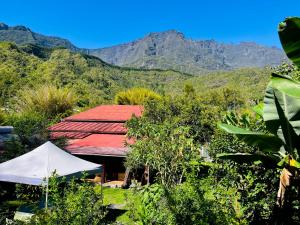 a building with a red roof with mountains in the background at La Kaz Yab in Salazie